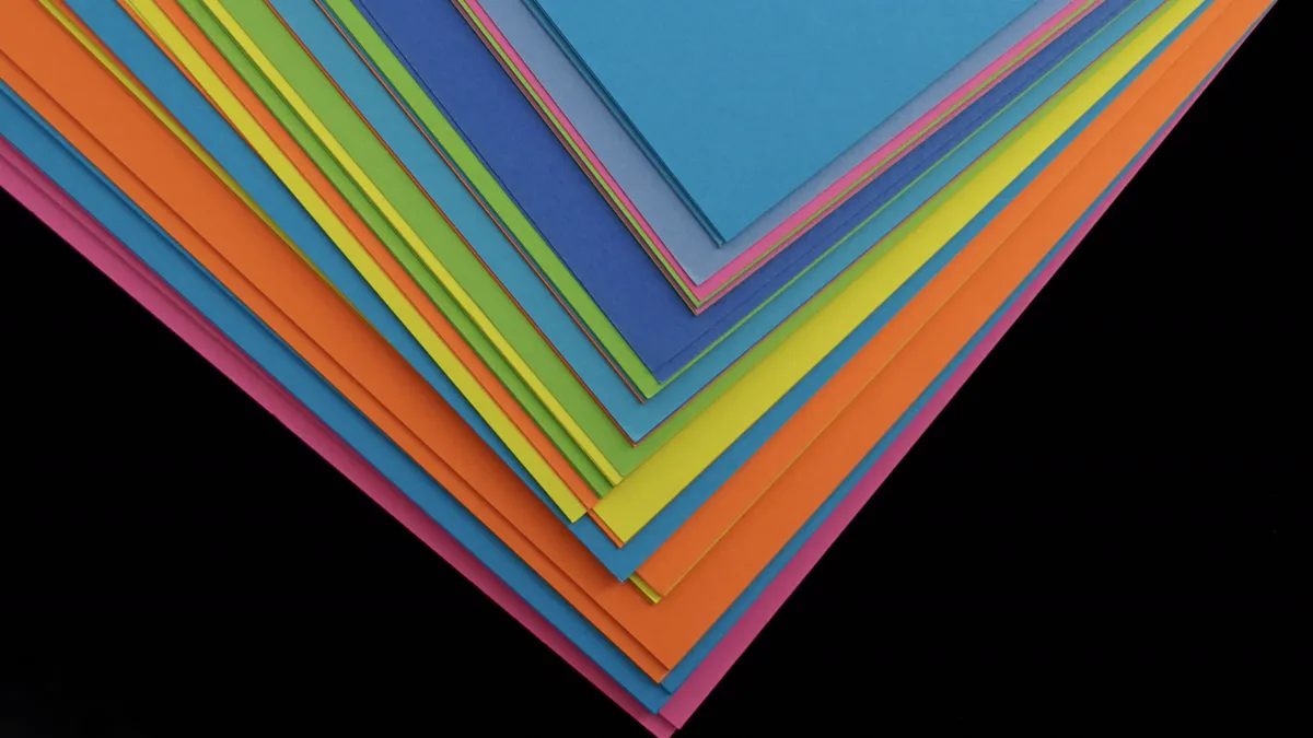 Fanned stack of blue, orange, yellow, green and pink coloured paper sheets on a black background