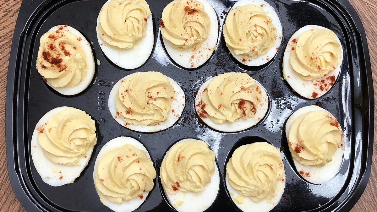 Deviled eggs piped into a black egg carrier tray ready to serve cold at a work potluck