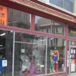 Costume shop front window with skeleton and superhero mannequins under a Halloween headquarters banner