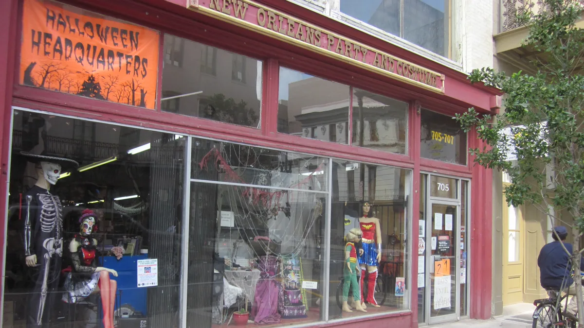 Costume shop front window with skeleton and superhero mannequins under a Halloween headquarters banner