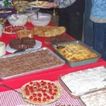Long potluck buffet table covered with trays of casseroles, desserts and salads for a staff holiday meal