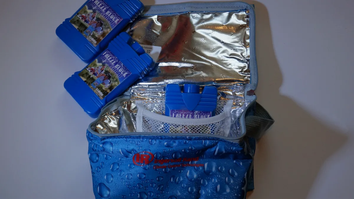 Open insulated lunch bag with frozen ice packs for a packed shift lunch Open blue insulated lunch bag with a foil lining and three hard frozen ice packs ready for a packed lunch