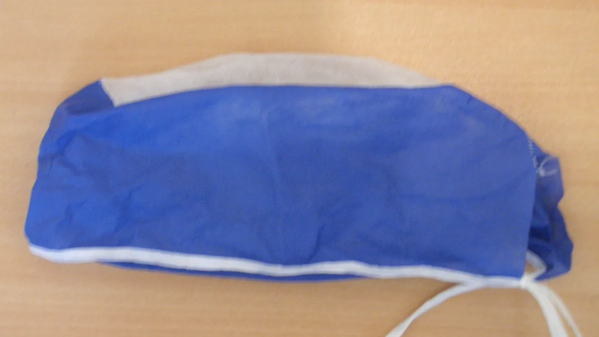 Blue and white tie-back scrub cap laid flat on a wooden table, a simple base for halloween costumes for nurses
