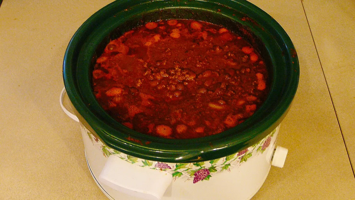 Floral slow cooker filled with bean chili on a counter, kept warm for a long shift potluck