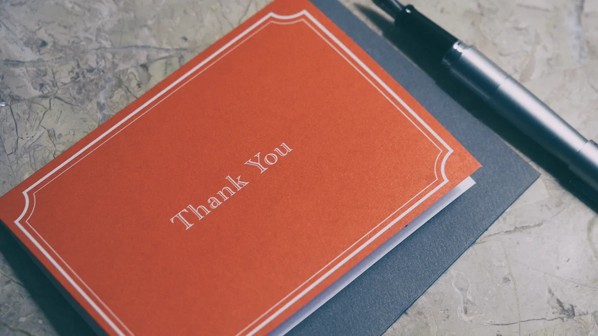 Orange thank you note to nurse staff resting on a grey envelope beside a silver fountain pen