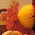 Retro paper turkey decoration with a honeycomb tail beside mini gourds, a simple Thanksgiving at work table idea