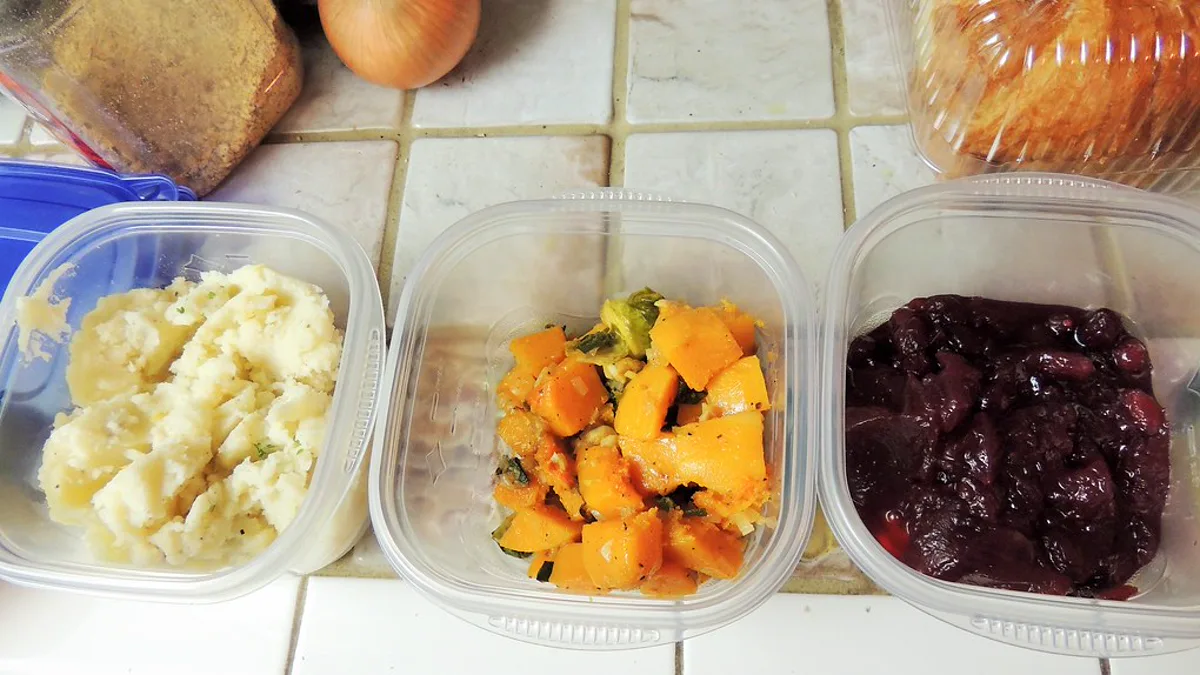 Mashed potatoes, roasted squash and cranberry sauce in clear plastic containers ready for lids and the refrigerator